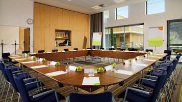 A conference room with a long table, blue chairs, and a clock on the wall.