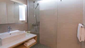 A modern bathroom with a large sink, mirror, and glass shower enclosure.
