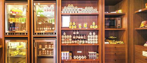 Zona de mercado con vitrinas refrigeradas y estantes llenos de diversos productos alimenticios.