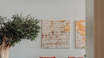 Un salón moderno con un sofá rojo, un árbol grande y arte abstracto en la pared.