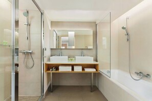 Une salle de bain moderne avec une douche à parois de verre, deux lavabos, un miroir et une baignoire.