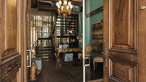 A room with a staircase, a chandelier, and a desk with a chair.