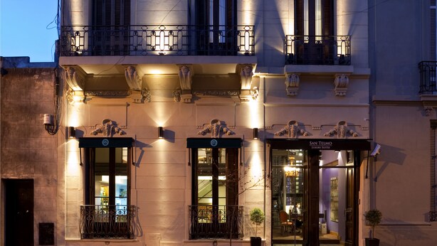 A building with a classical facade, featuring ornate balconies and a storefront with a sign reading "San Telmo Luxury Suites".