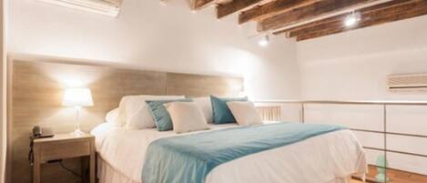 A bedroom with a bed, bedside table, and a wooden ceiling structure.