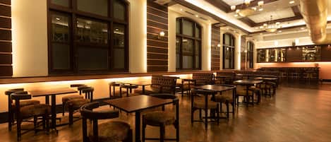 Un restaurante espacioso con techos altos, amplias ventanas y diversas opciones de asientos, como mesas y cabinas.
