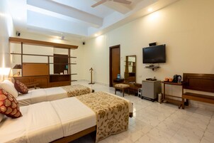 A hotel room with two beds, a TV, a desk, and a mirror.
