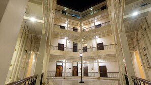 Un atrium de diversos nivells amb una làmpada central, diversos balcons i un paviment polit.