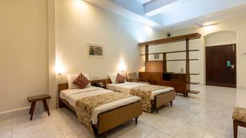 A hotel room with two beds, a small table, a desk, and a wardrobe.
