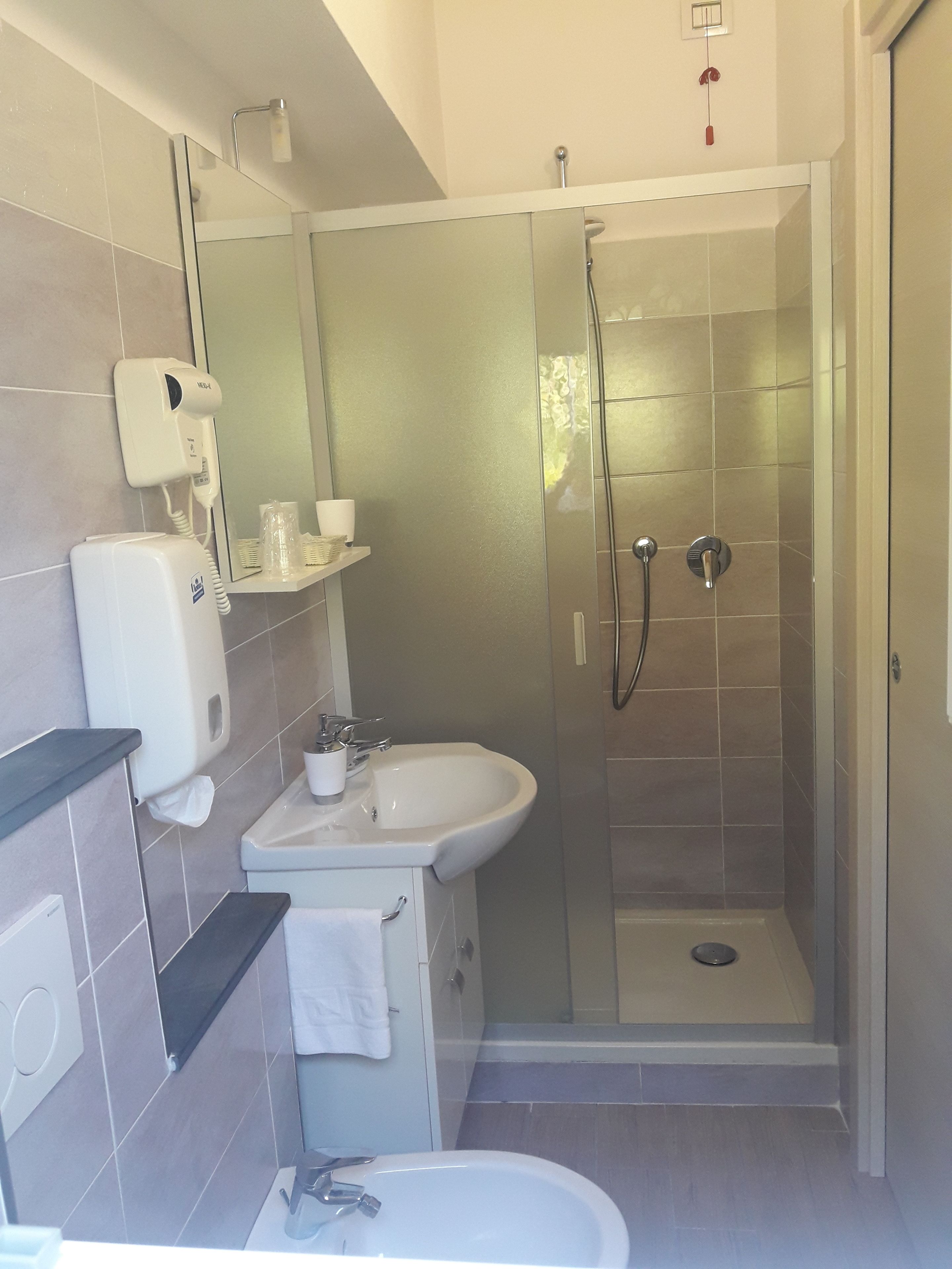 Ein modernes Badezimmer mit einer Duschkabine, einem Waschbecken und einem Handtrockner.