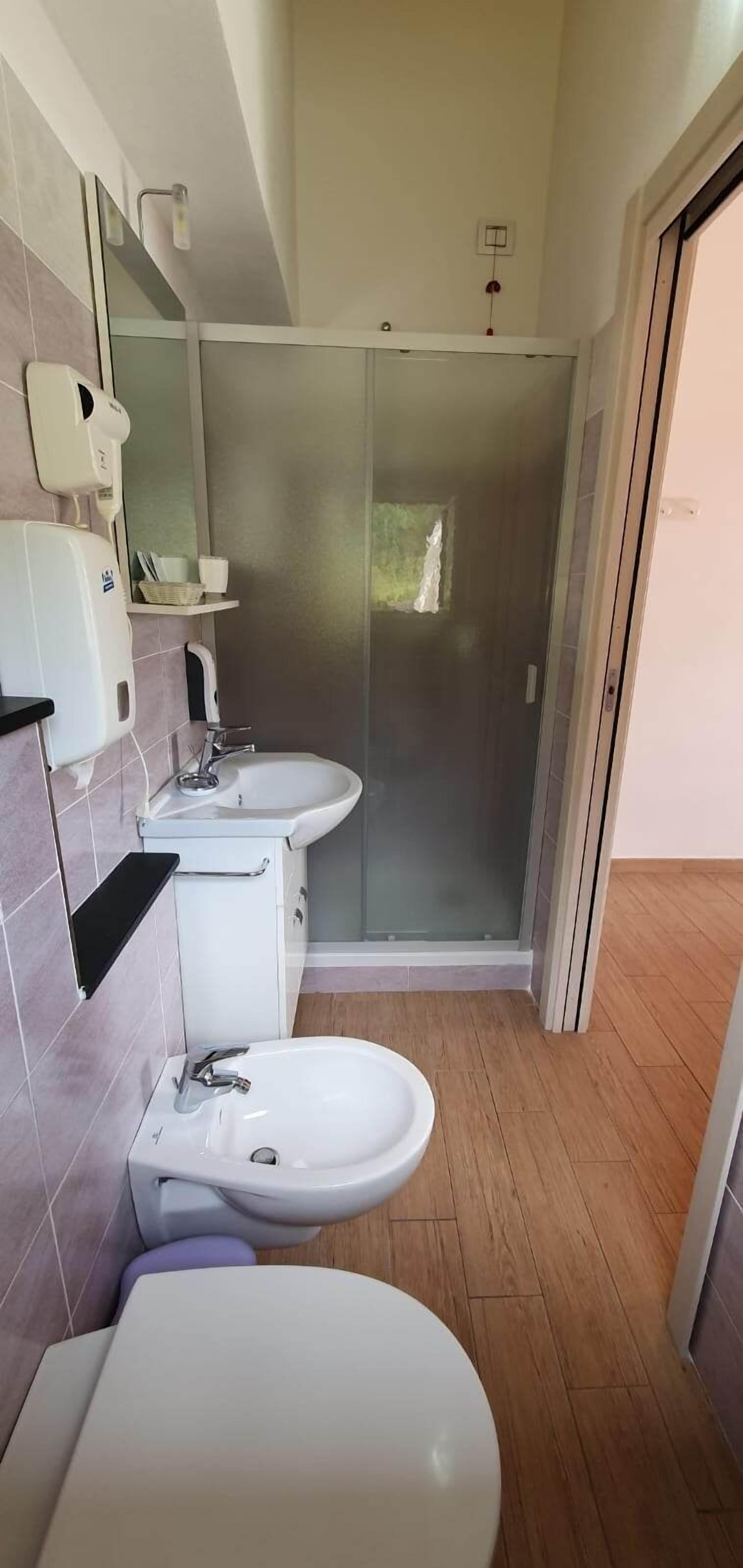 Een badkamer met twee wasbakken, een spiegel, een handdoekhouder en een douchecabine.