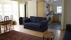 En stue med sofa, rundt sofabord og spiseområde med stole og bord.