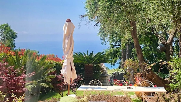 A patio area with a table and chairs, surrounded by potted plants and a view of the sea. - La Finestra sul Mare (Bordighera)