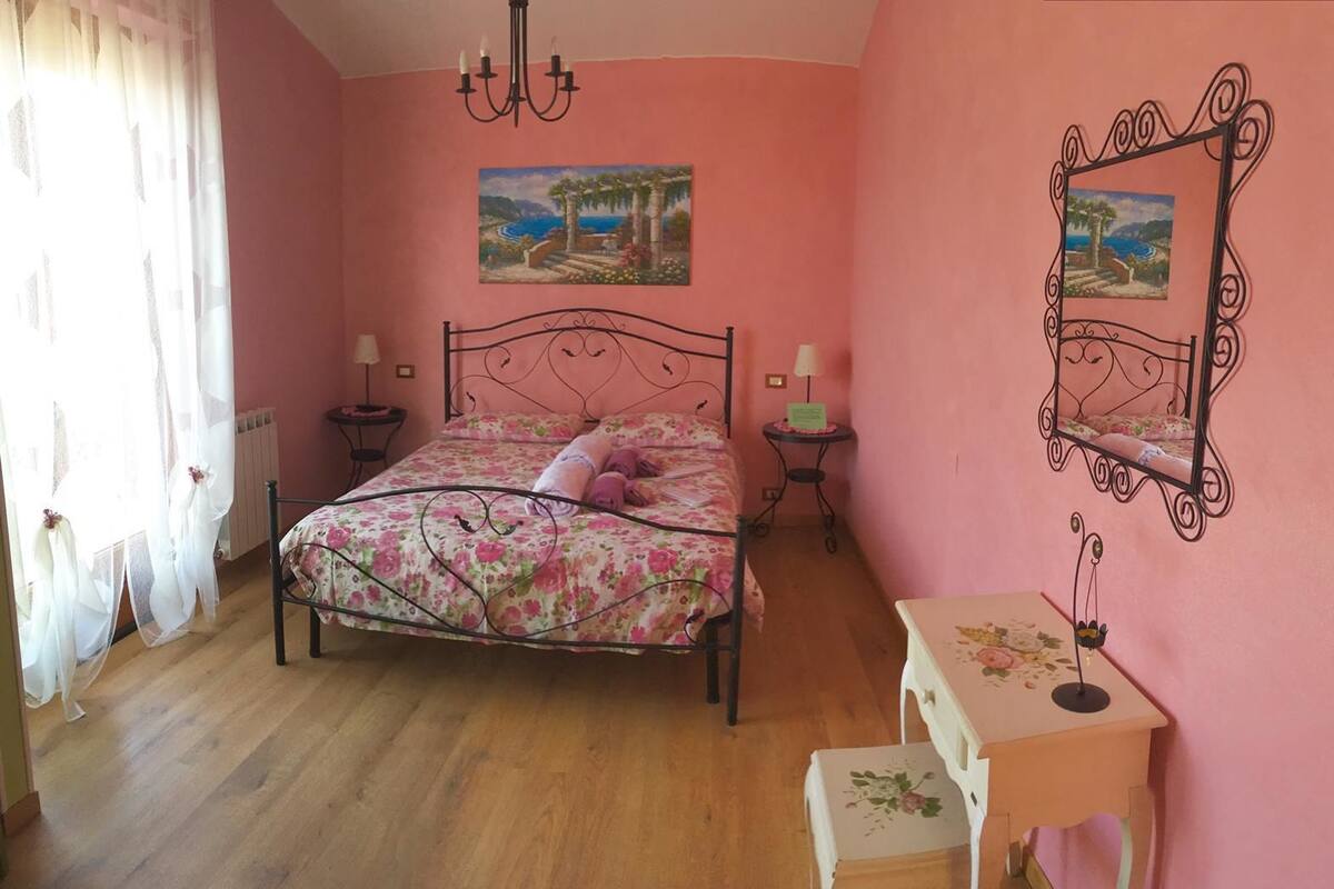 A bedroom with a bed, bedside tables, a desk, and two wall-mounted paintings.