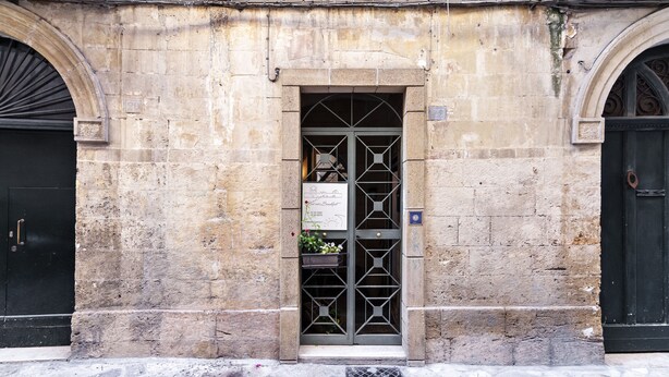 A stone building with a central entrance featuring a metal gate and a flower box.