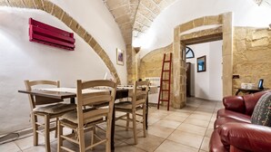 A dining area with a table and chairs, a red air conditioning unit, and a stone wall.