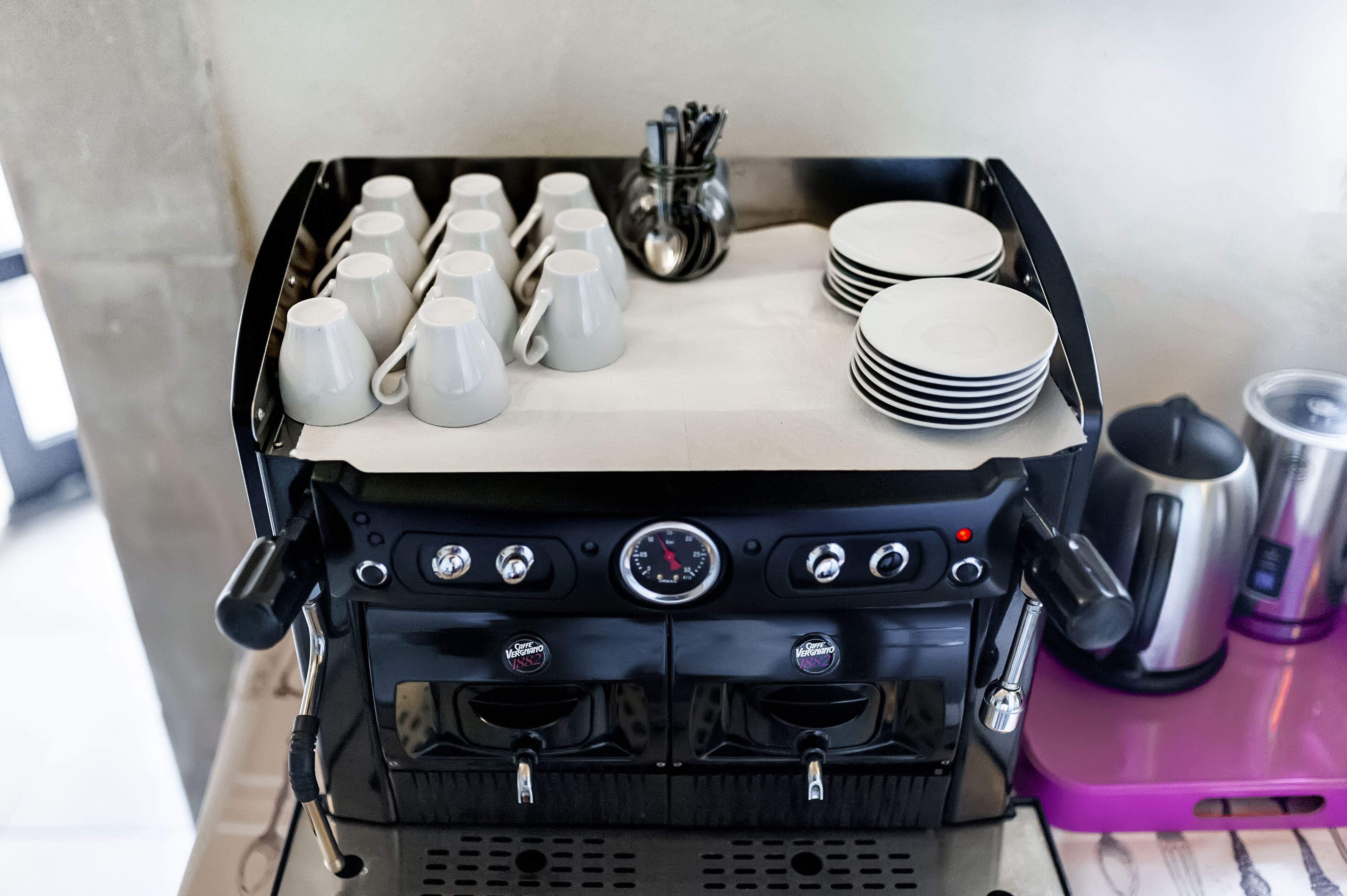 Una macchina da caffè con diverse funzioni, un vassoio con tazze e piatti e una termosi.