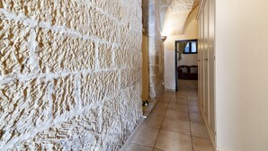 A hallway with textured stone walls and a tiled floor.