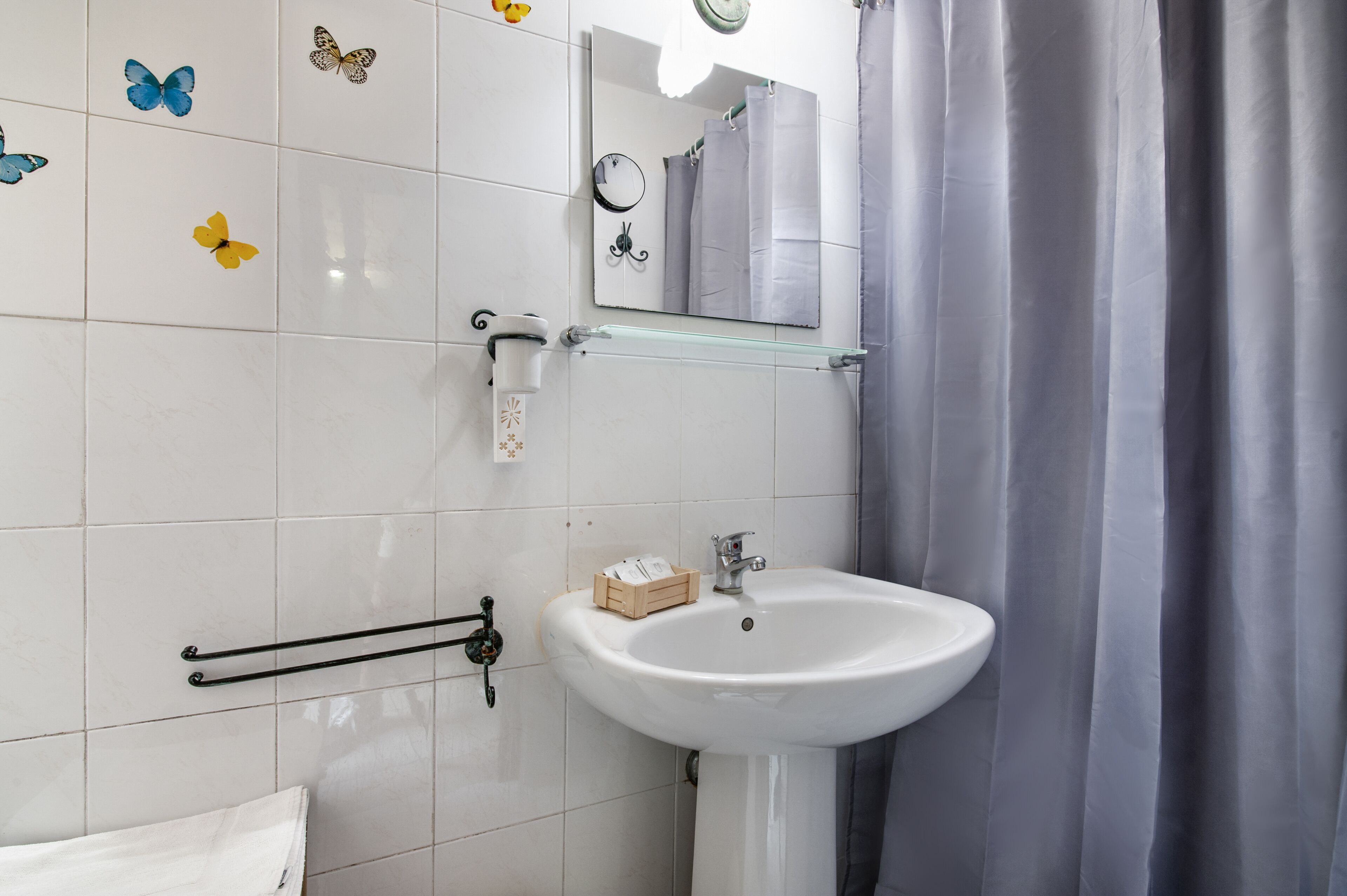 A bathroom with a white sink, a mirror, and a shower curtain.