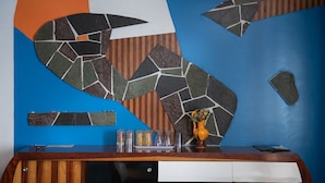 Balcão de recepção com parede azul, armário de madeira e um objeto decorativo na parede.