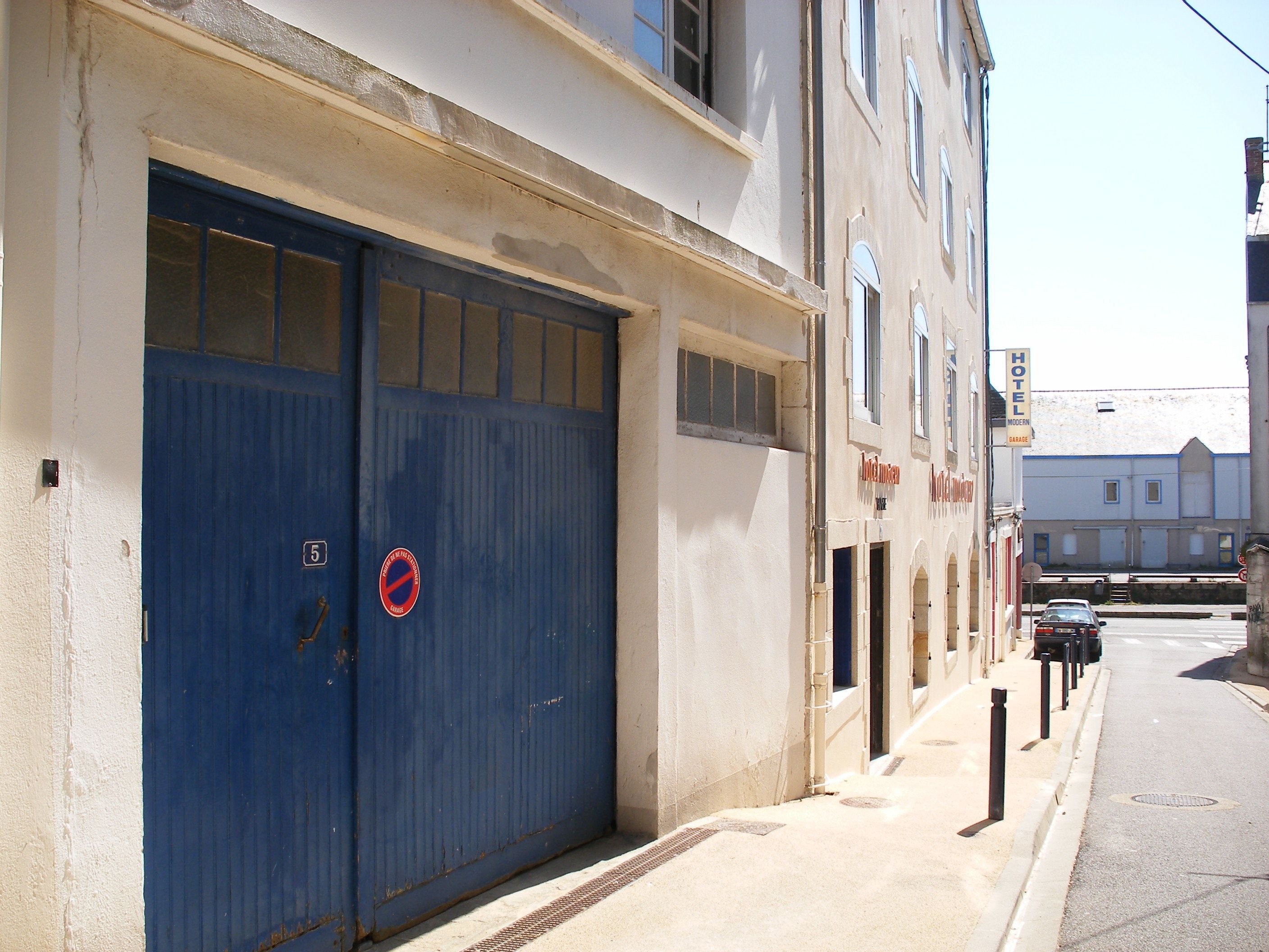 A building with a blue garage door, a sign indicating a hotel, and a modern garage.