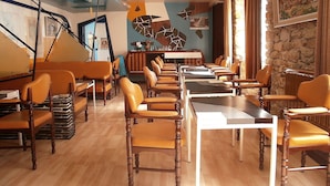 Um restaurante com mesas e cadeiras de madeira, um espaço de bar e uma parede de pedra com uma pintura.