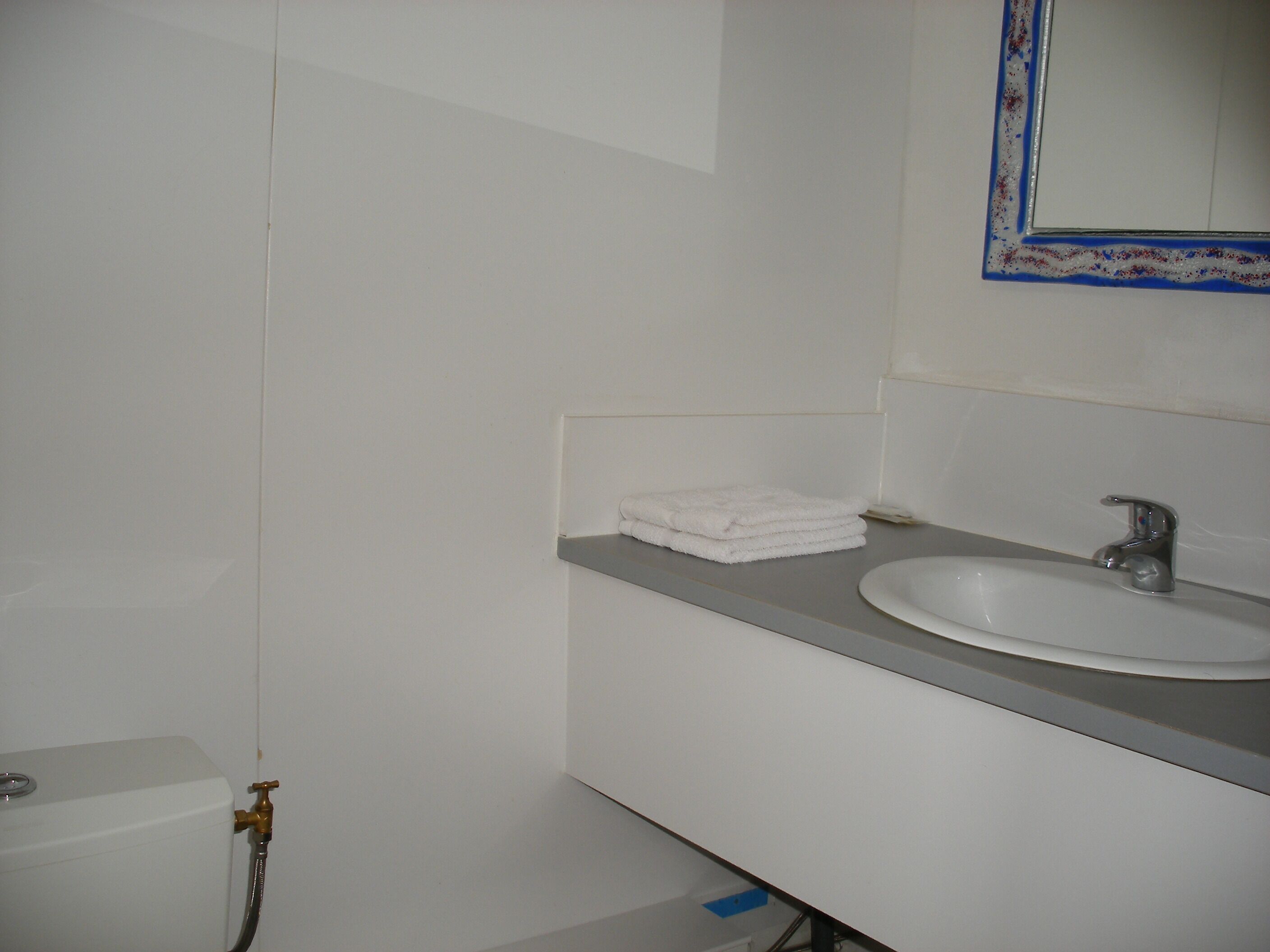 A bathroom with a white sink, a mirror with a blue frame, and a toilet.
