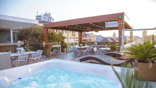 Zona de piscina en la azotea con sillones reclinables y una zona de estar techada.