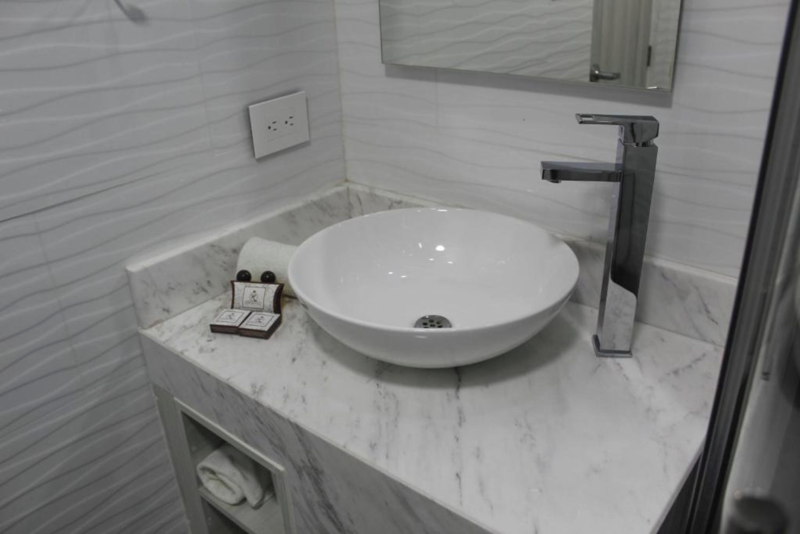 A bathroom with a white sink, a mirror, and a towel rack.