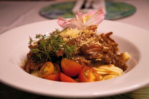 A plate of food with meat, tomatoes, and a garnish.