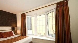 Een hotelkamer met een groot bed, een raam met gordijnen en uitzicht op buiten.