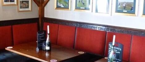 Un restaurante con mesas de madera y asientos tapizados en rojo.