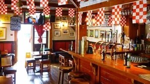 Een bar met geruite vlaggen, krukken en een toog met flessen en glazen.