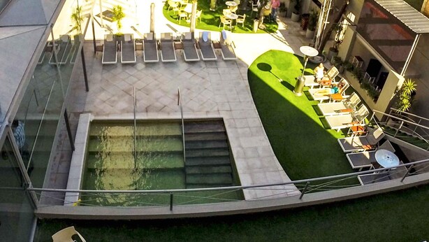 A rooftop pool area with lounge chairs, a small table, and a grassy section. - Platino Termas All Inclusive (Termas de Rio Hondo)