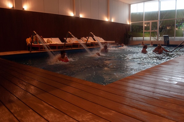 Una piscina cubierta, una piscina al aire libre, sombrillas