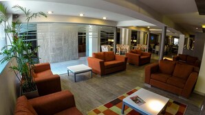A modern lounge area with orange sofas, a coffee table, and a colorful rug.
