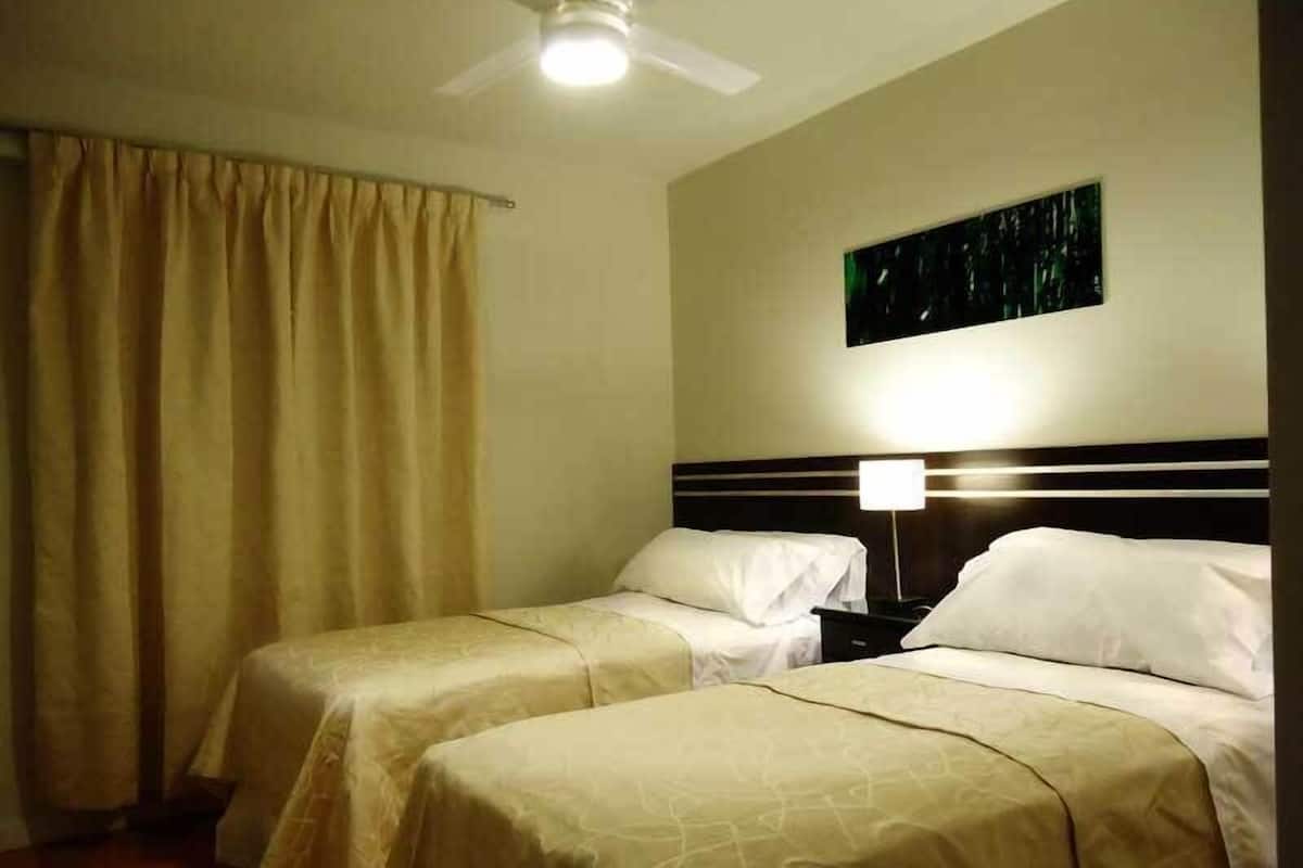 A hotel room with two beds, a ceiling fan, and a night light.