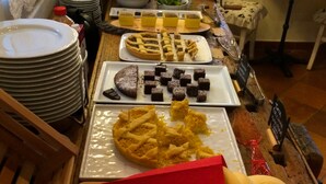 Una mesa de buffet con diversos platos, entre ellos una tarta, brownies y una selección de quesos.
