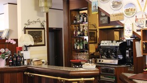 A bar area with a coffee machine, shelves of bottles, and a framed picture on the wall. - Locanda da Renzo (Treviso)
