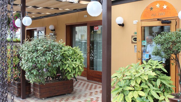 A building entrance with a wooden door, a sign indicating the year 1969, and potted plants in front. - Locanda da Renzo (Treviso)