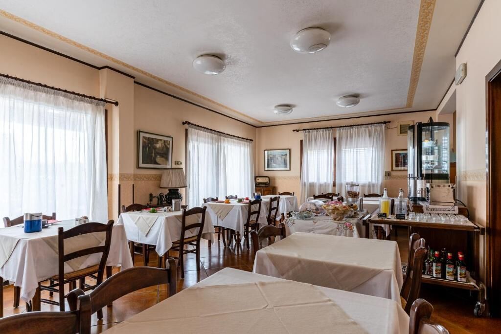 Een eetgedeelte met tafels voor maaltijden, een keuken met apparatuur, en een aanrecht met diverse spullen.