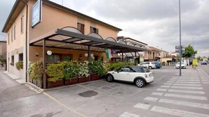 A hotel with a covered outdoor area, a car parked in front, and a pedestrian crossing. - Locanda da Renzo (Treviso)