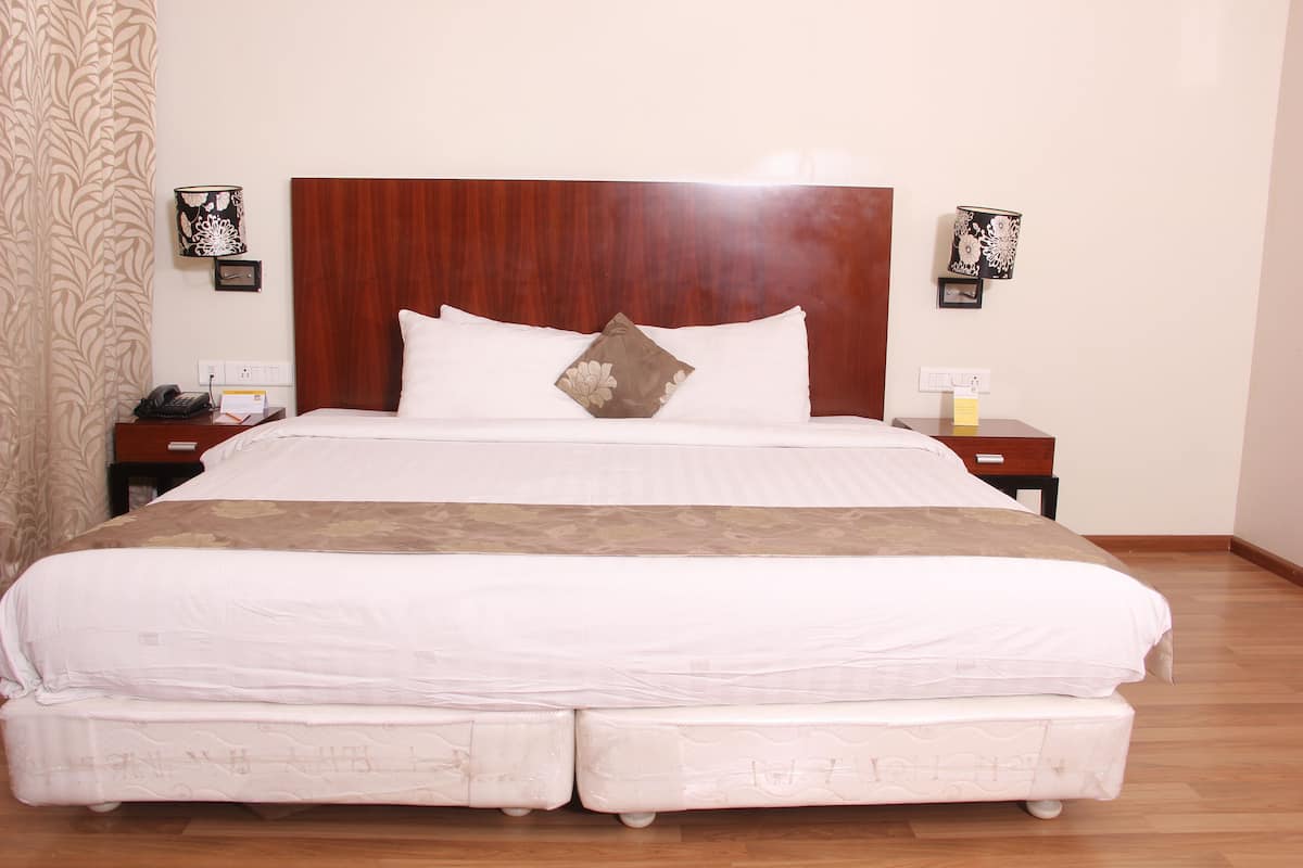 A large bed with a wooden headboard, white bedding, and a decorative pillow. There are two bedside tables with lamps and a telephone on one.