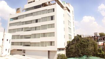 Un edificio de varios pisos con fachada plana, ventanas amplias y un letrero que indica que es un hotel.