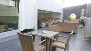 An outdoor seating area with wicker furniture and a glass table. - The Aures (Chhatrapati Sambhajinagar)