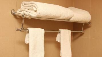 A bathroom with a towel rack holding two rolled towels and two hanging towels.