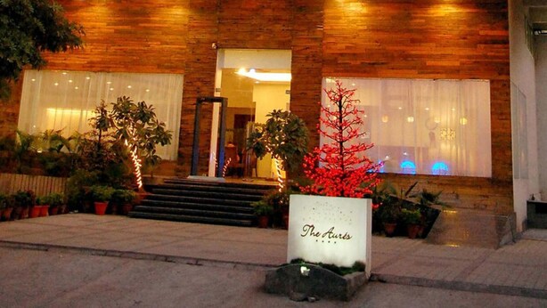 A hotel entrance with a wooden facade, steps leading up to the door, and potted plants. - The Aures (Chhatrapati Sambhajinagar)