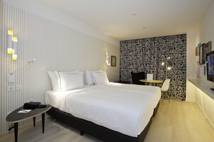 Ett modernt hotellrum med en stor säng, ett skrivbord och en stol.