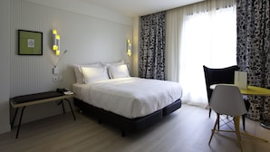 Une chambre d’hôtel moderne avec un grand lit, une table de chevet et un bureau avec une chaise.