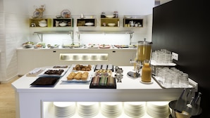 Ein reichhaltiges Buffet mit verschiedenen Speisen, einem Getränkespender und einem Weinkühler.