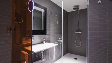 A modern bathroom with a glass-enclosed shower, a white sink, and a large mirror.